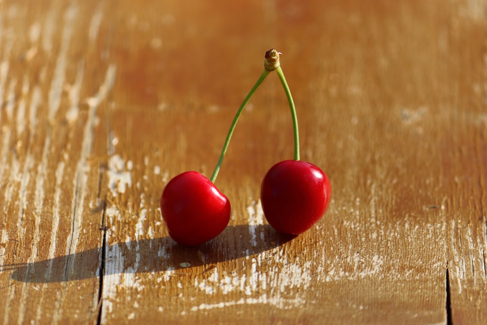 two cherries sitting on top of a wooden table