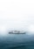 A large ferry labeled 'We Love Indonesia' sails on a calm expanse of water. The sky is overcast, creating a muted and serene atmosphere.
