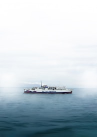 A large ferry labeled 'We Love Indonesia' sails on a calm expanse of water. The sky is overcast, creating a muted and serene atmosphere.