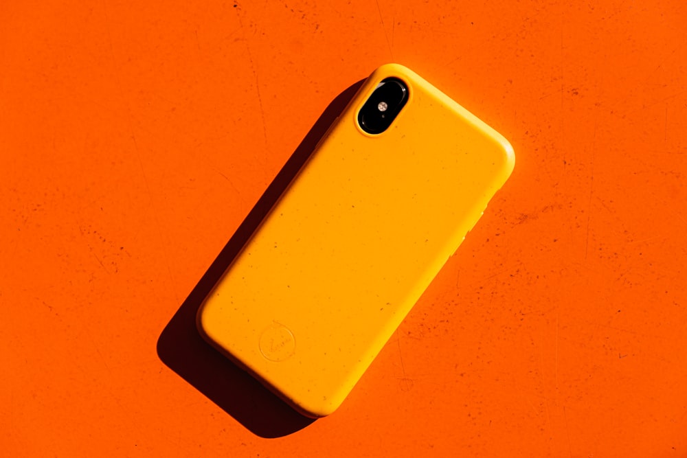 un teléfono celular amarillo sobre una superficie naranja