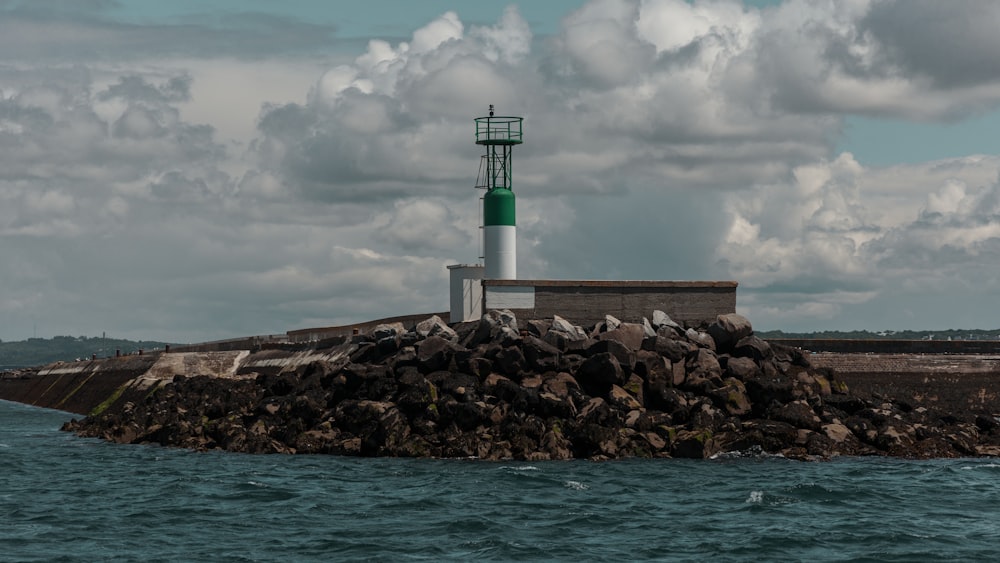 a green and white light house sitting on top of a small island