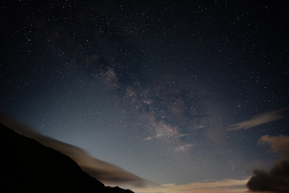 the night sky with stars above a mountain