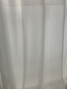 Close-up of a sleek motorized curtain track installed above a large window with sunlight filtering through.