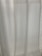 A close-up view of light-colored curtains with vertical pleats, allowing diffused light to pass through.