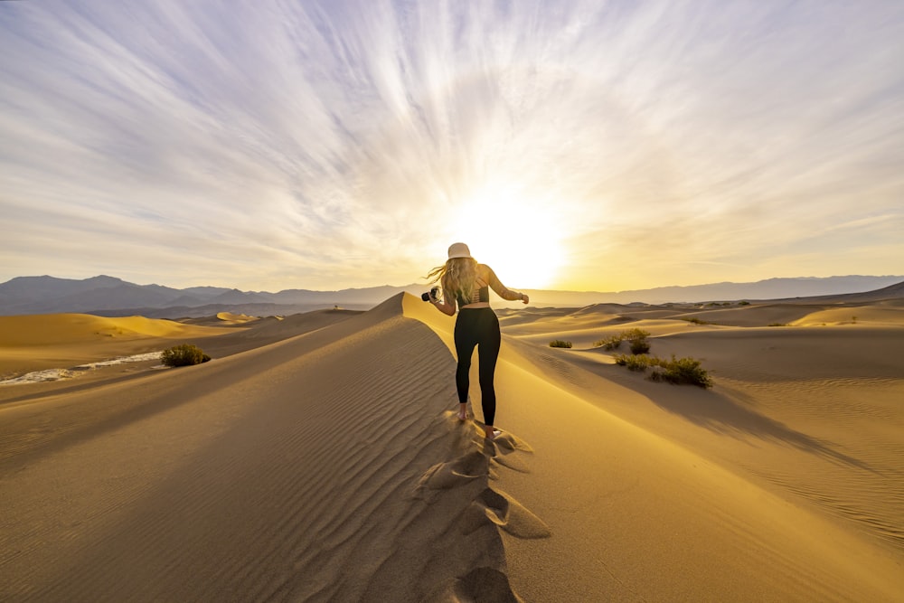 a woman standing on top of a sand dune