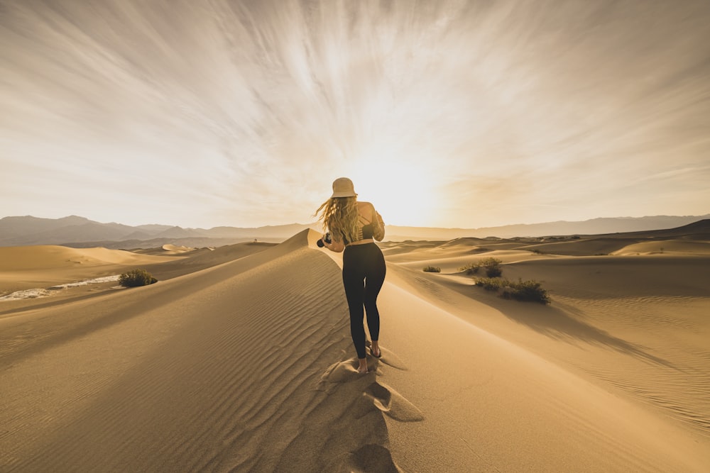 Una donna che cammina attraverso un campo di sabbia del deserto
