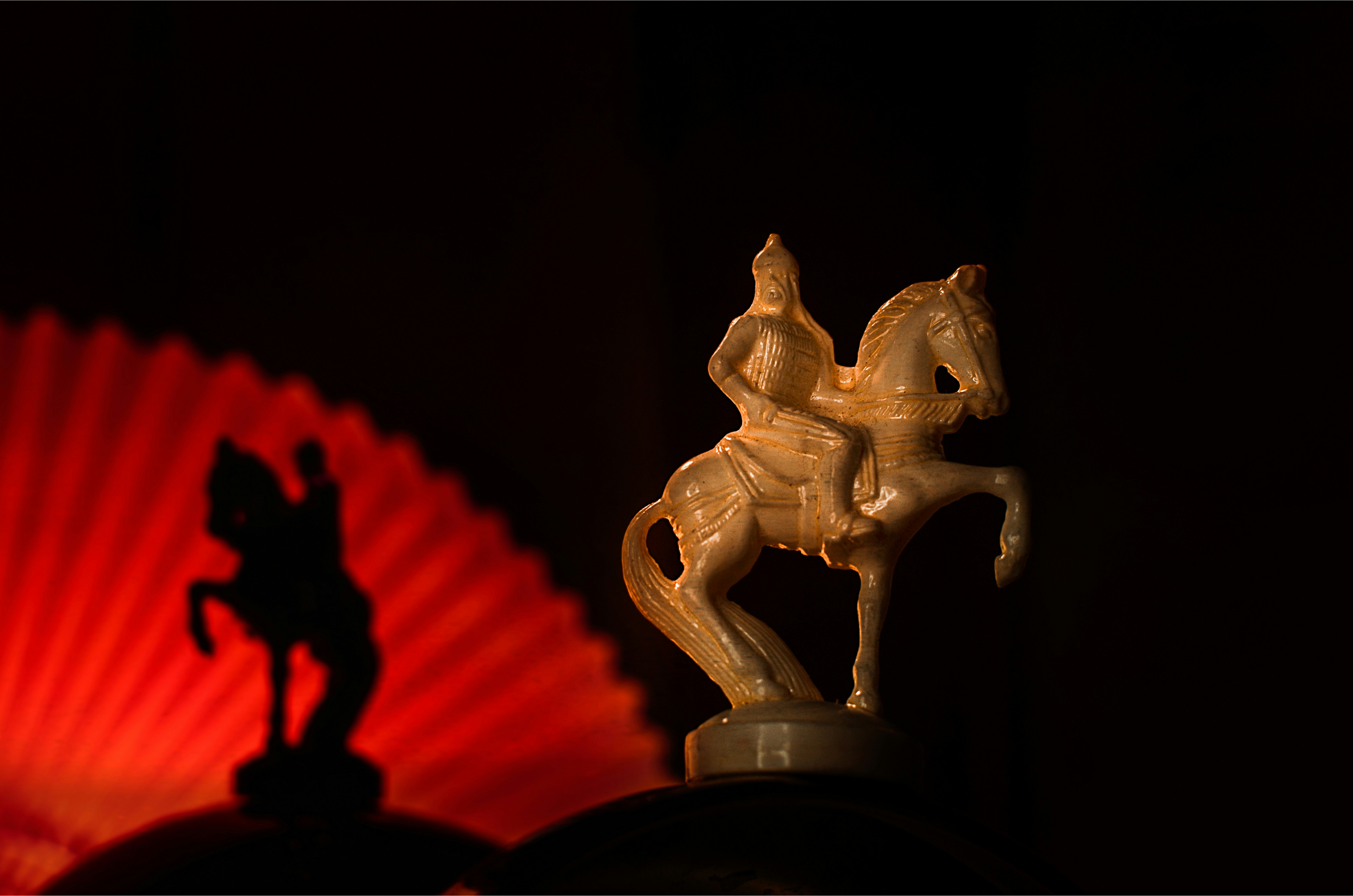 a statue of a man riding a horse next to a red fan