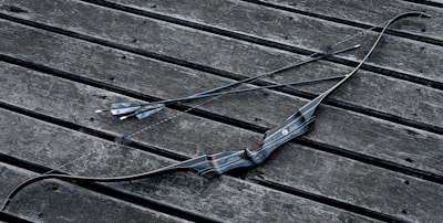 A modern compound bow featuring its pulley system, resting on a wooden table with arrows.