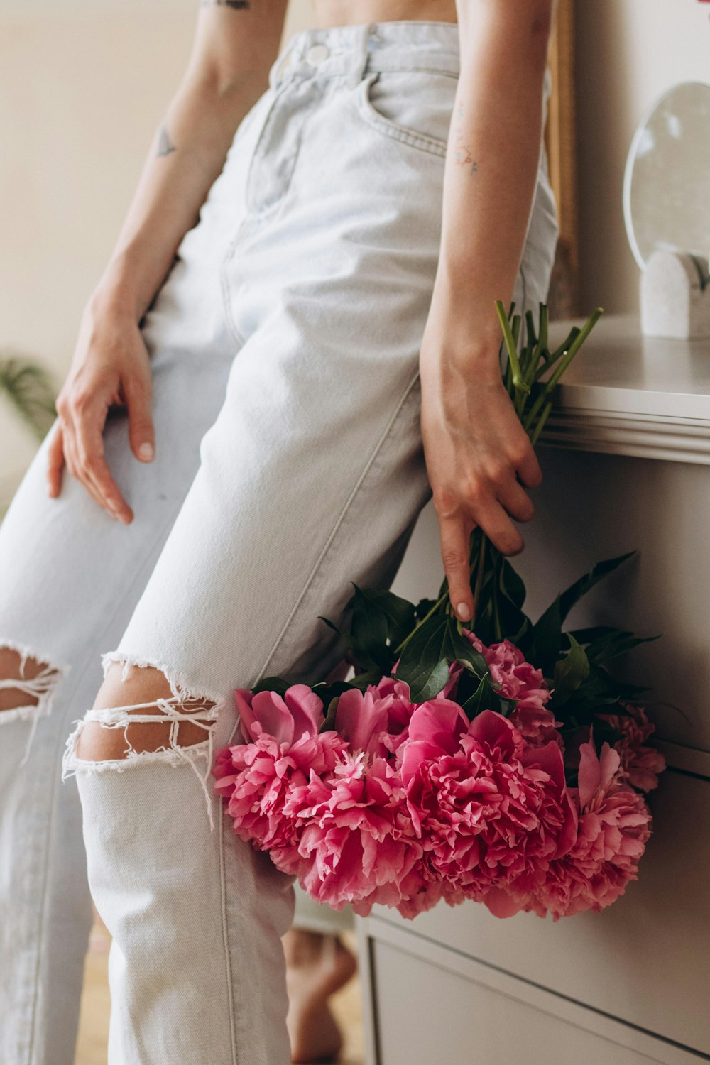 a woman sitting on a dresser holding a bouquet of flowers