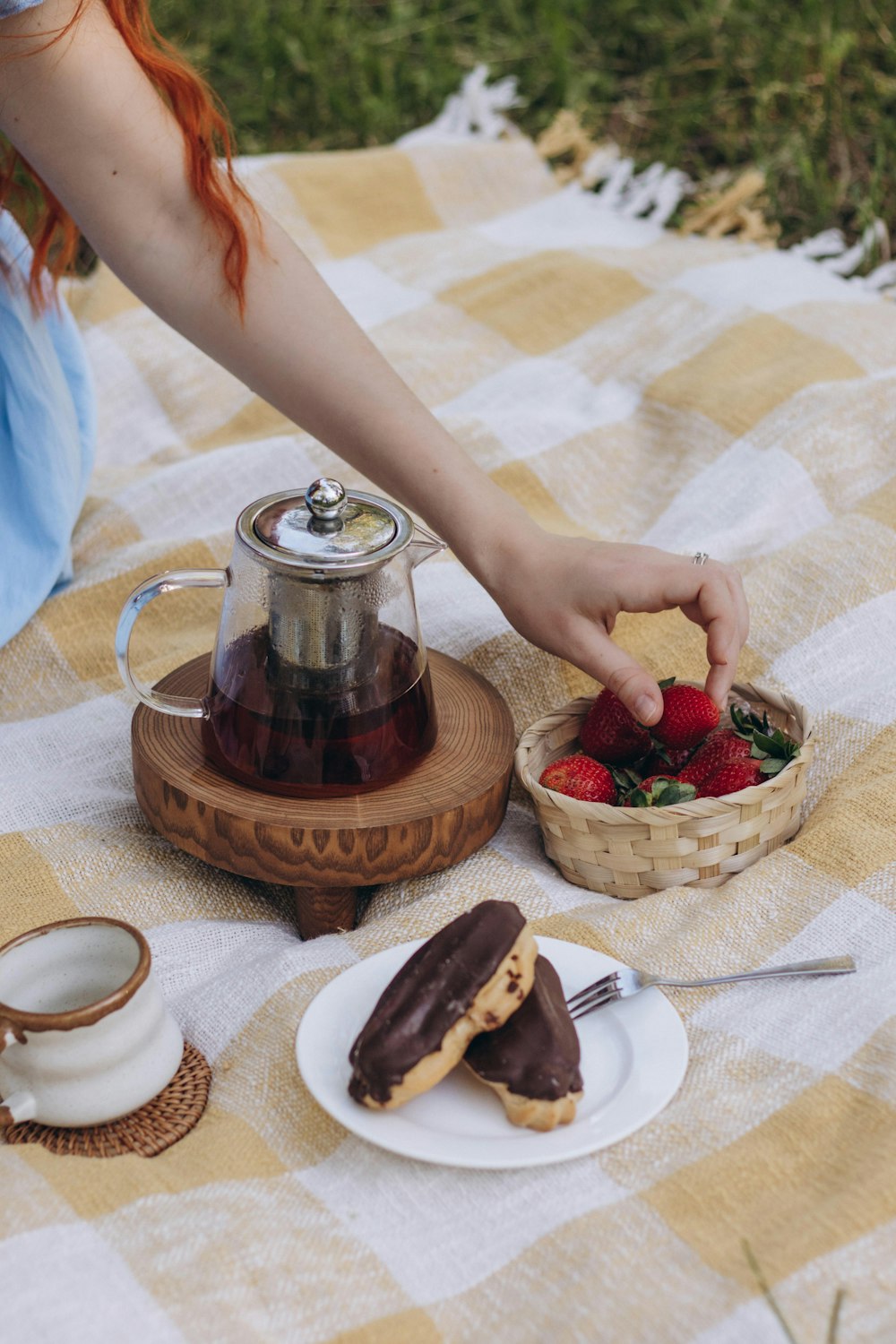 a woman sitting on a blanket with a basket of strawberries