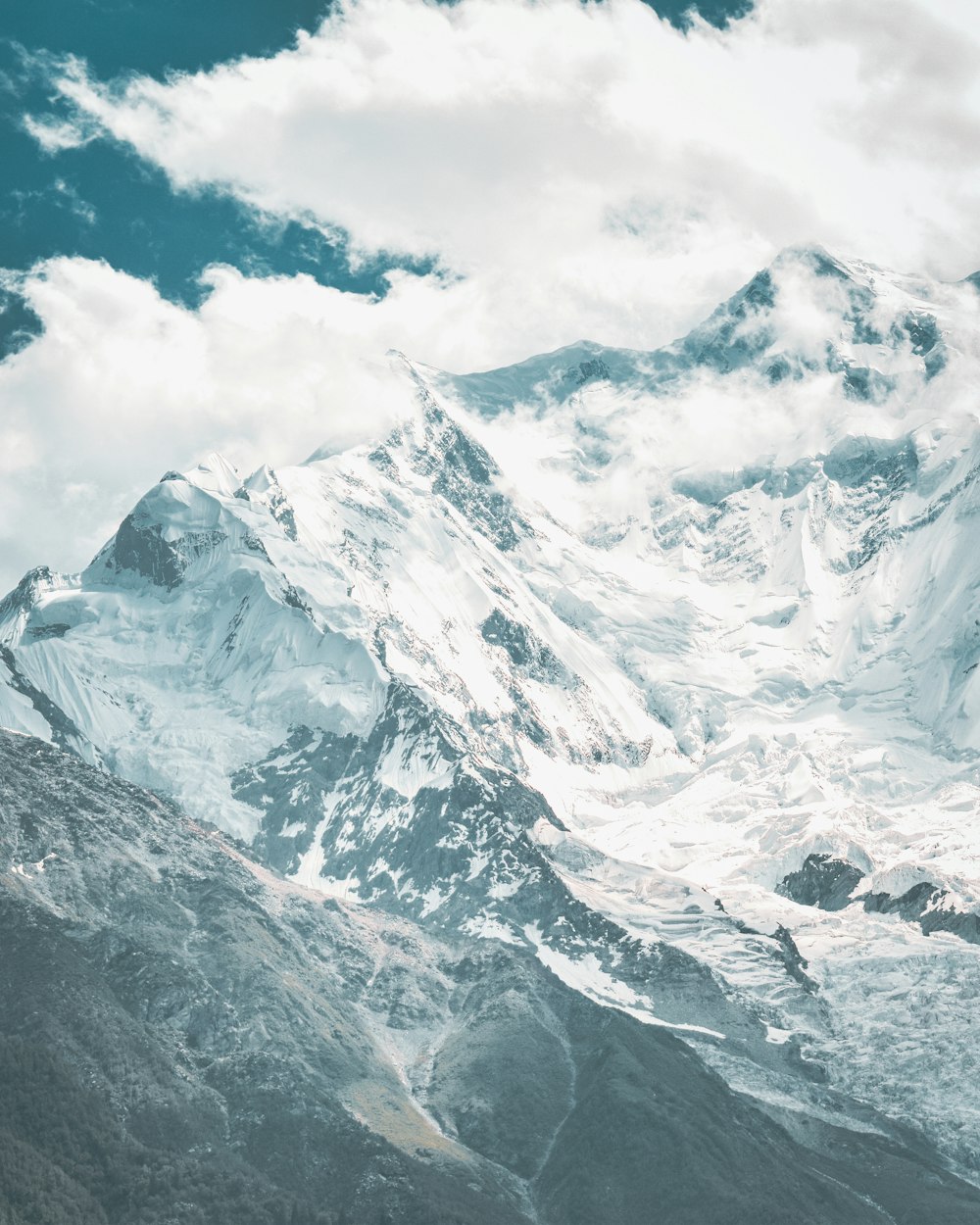 a large mountain covered in snow under a cloudy sky