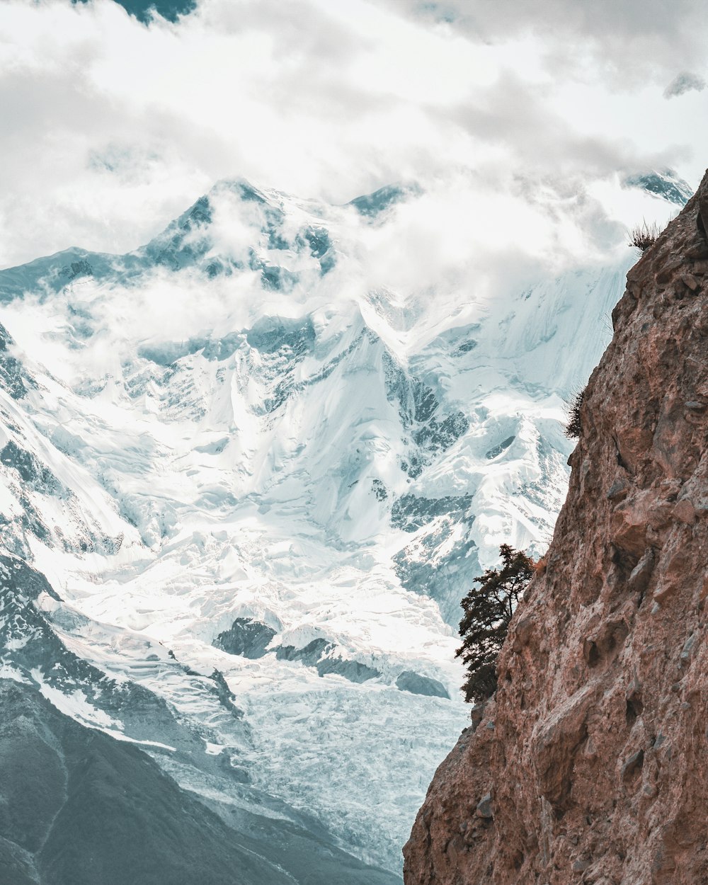 um homem de pé no topo de uma montanha ao lado de uma montanha coberta de neve