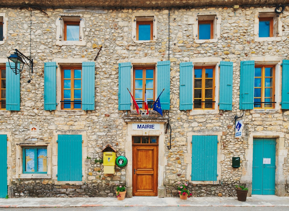 ein Steingebäude mit blauen Fensterläden und einer Holztür