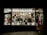 A store display filled with various Halloween costumes and decorations, featuring multiple mannequin heads wearing different masks and wigs. The window is brightly lit, showcasing colorful costumes, spooky masks, and accessories with a slightly eerie ambiance.