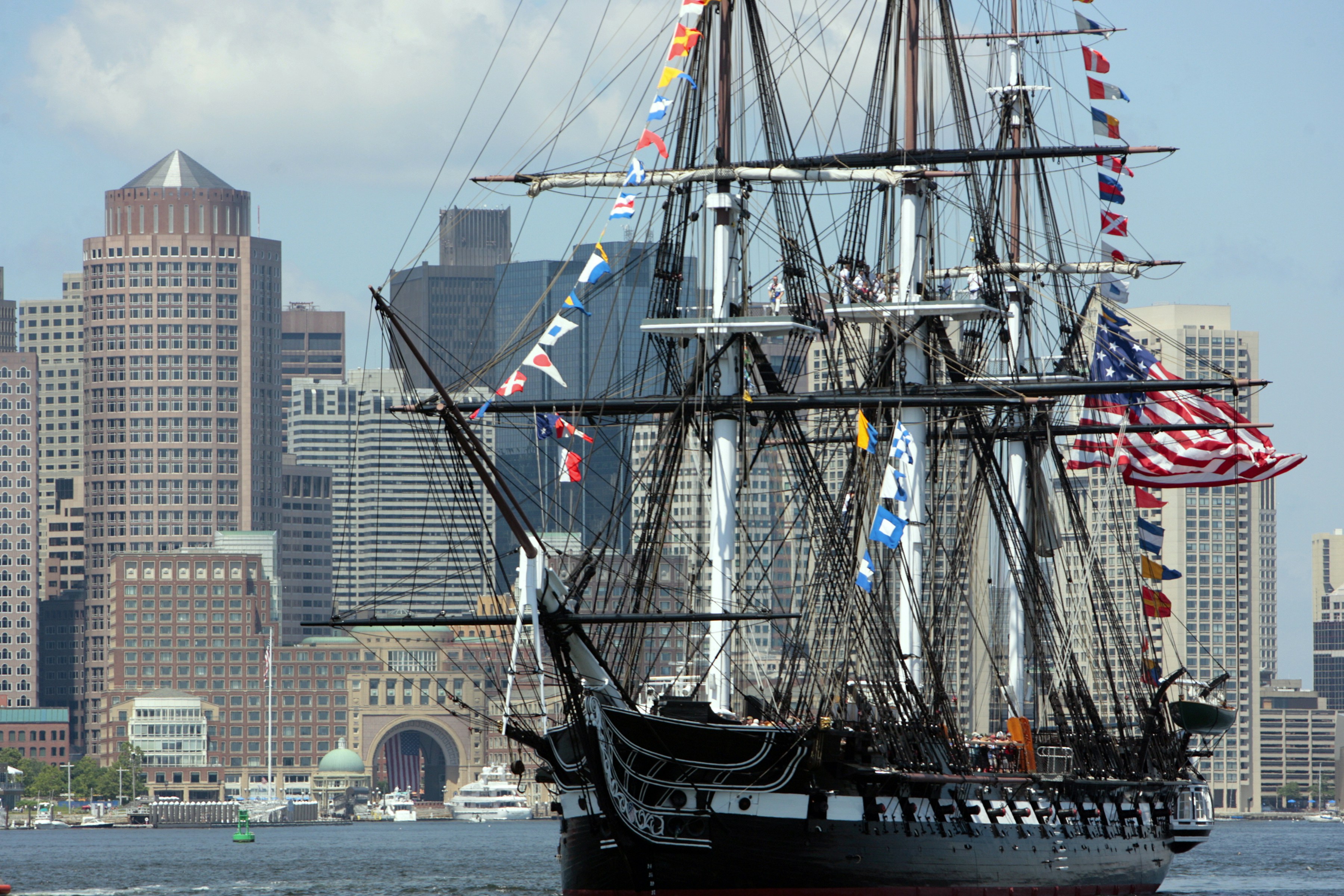 a large sailing ship in the water with a city in the background, 