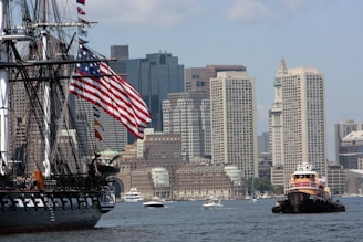 a large boat in a body of water with a city in the background