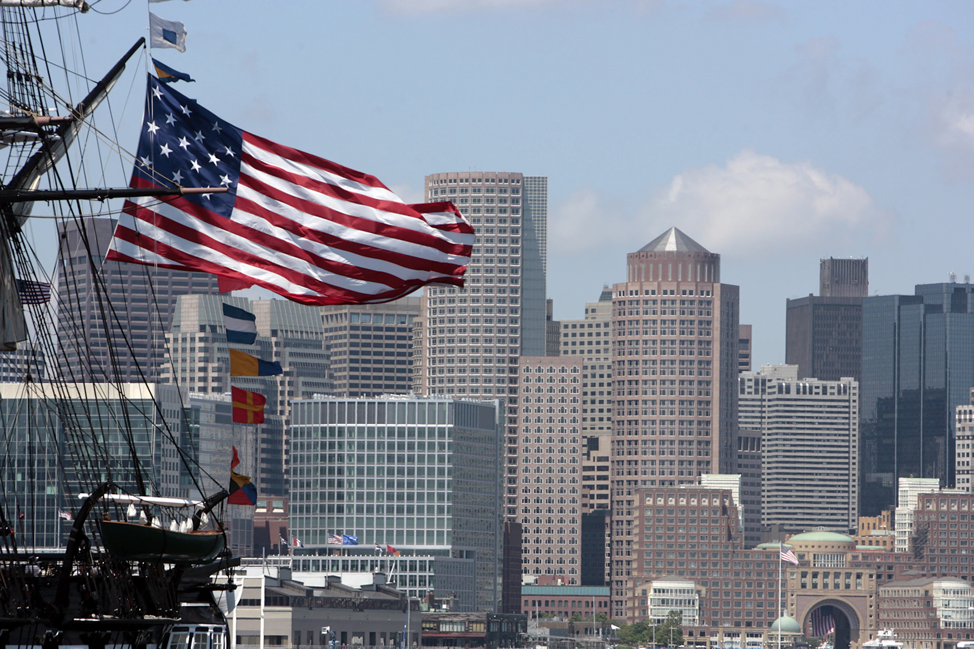 a large american flag flying in front of a city