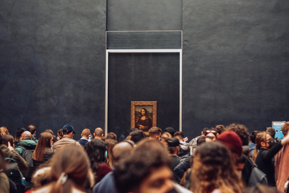 a crowd of people standing in front of a painting