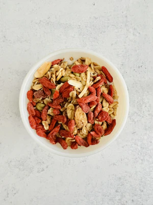 Close-up of a vibrant bowl filled with freshly made panjeeri sprinkled with nuts and seeds on a rustic wooden table
