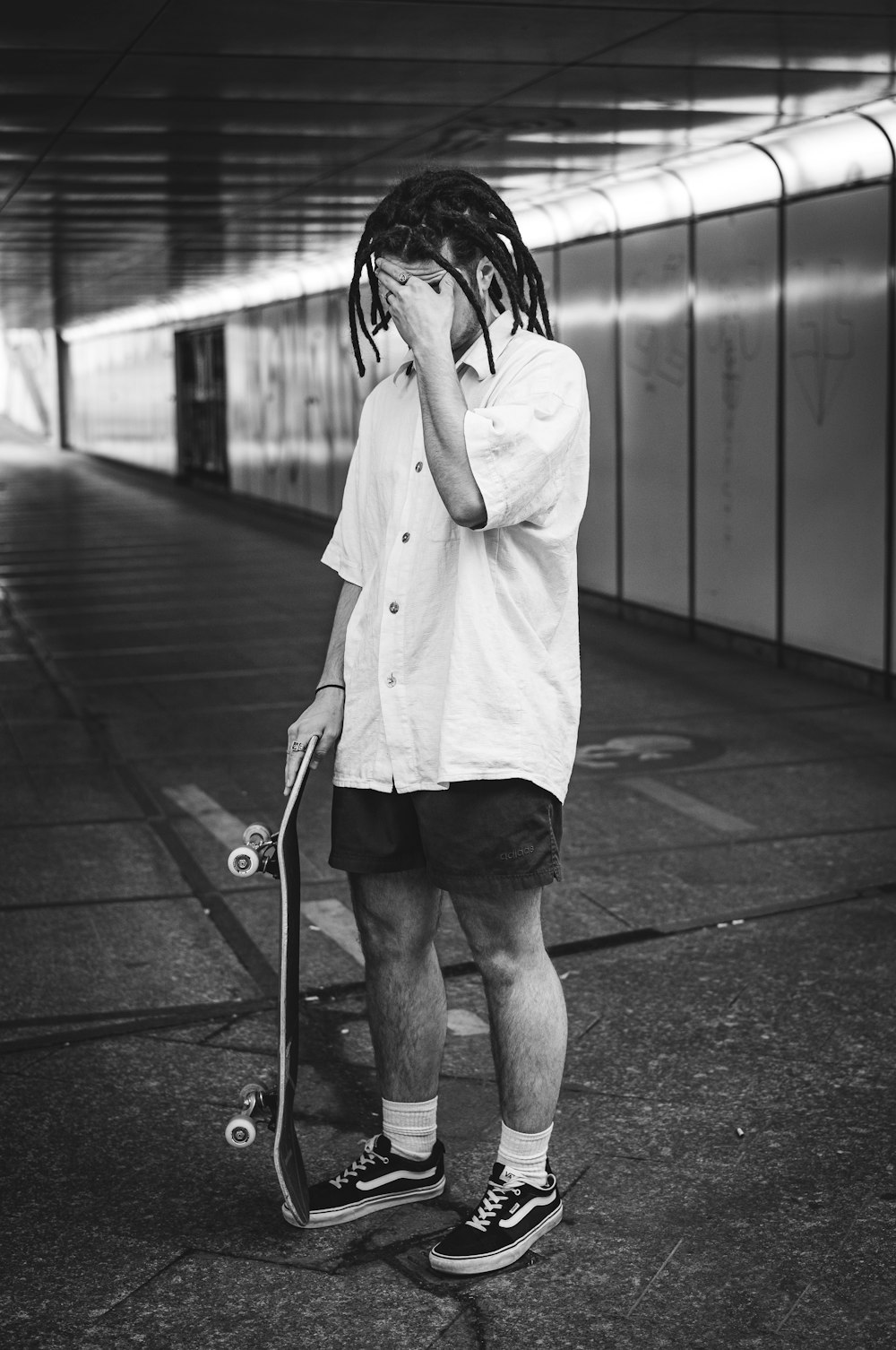 a man with dreadlocks is holding a skateboard