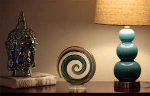 a table with a lamp, a book and a vase on it