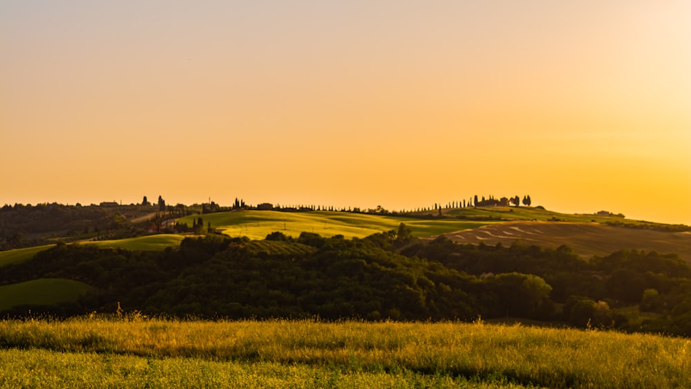 the sun is setting over the rolling hills