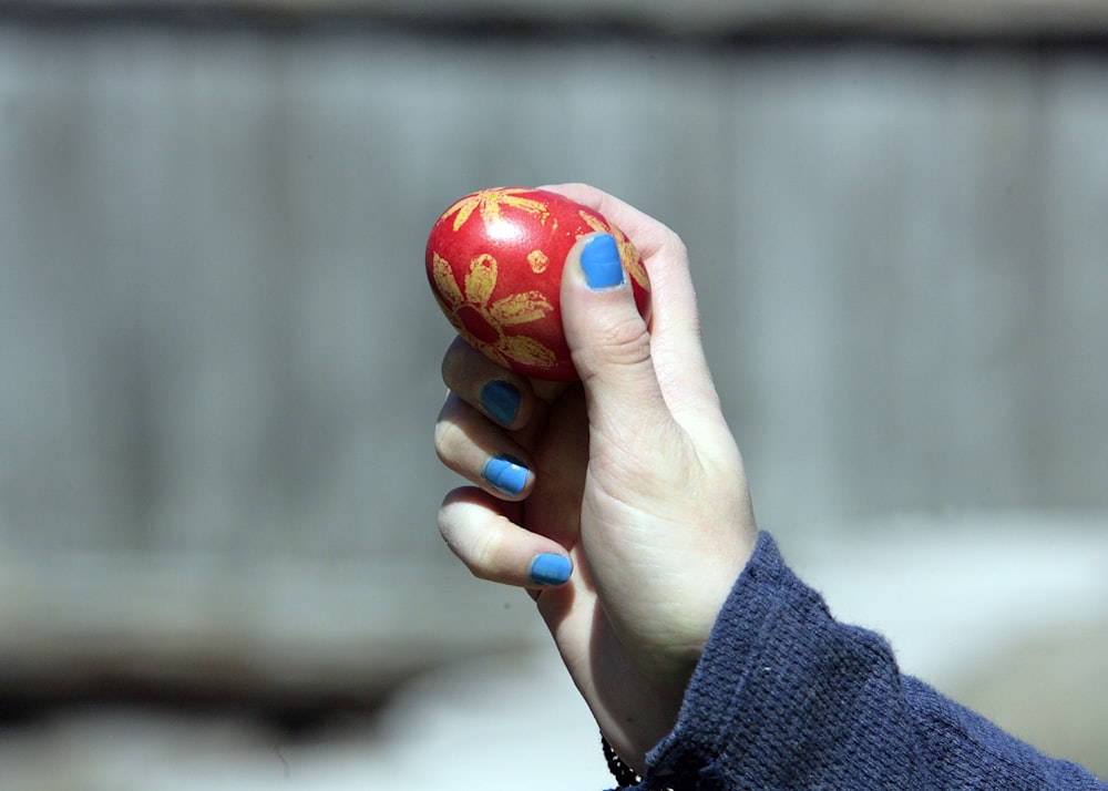 a woman's hand holding a red heart shaped object