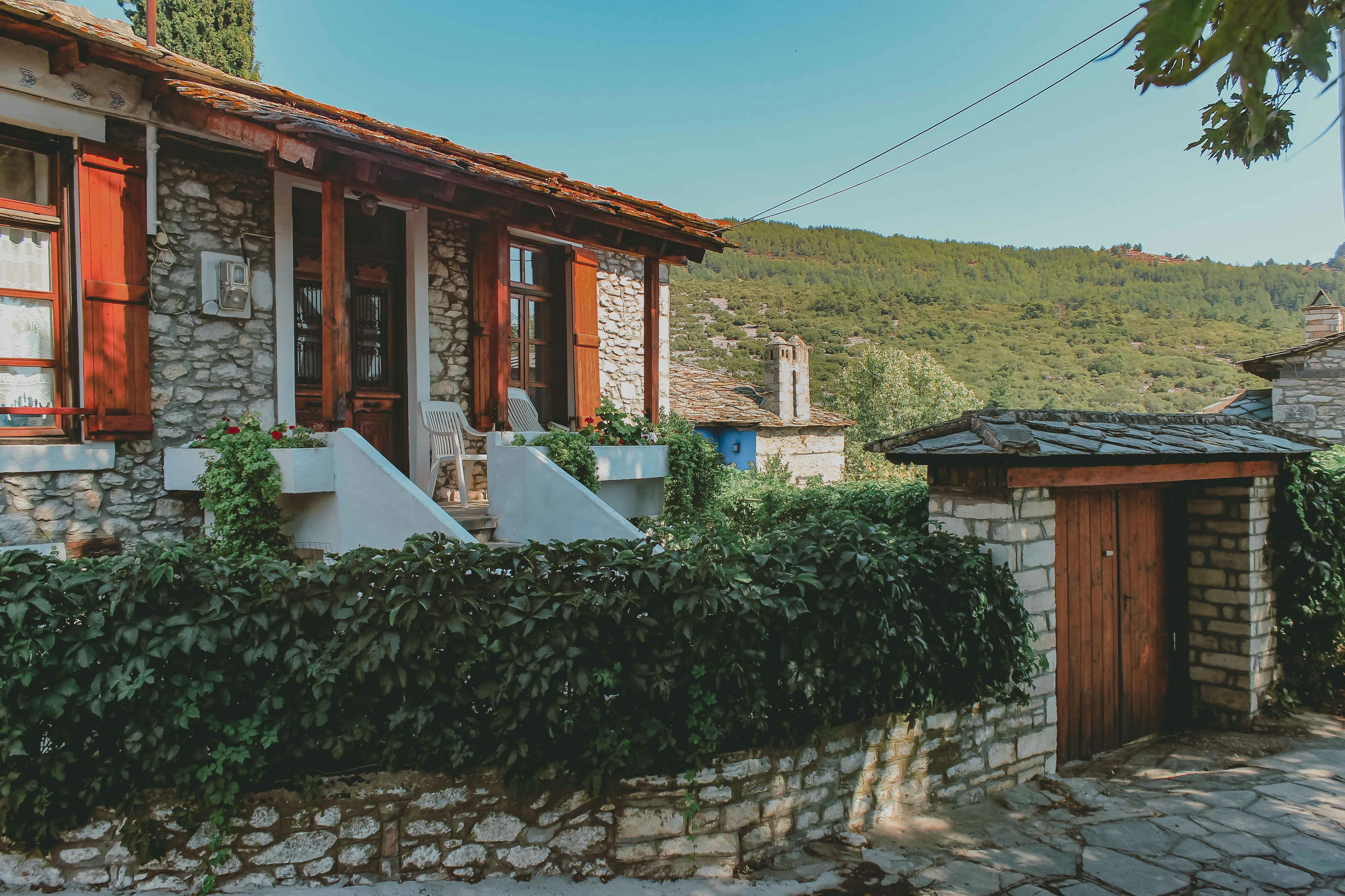 a stone house with red shutters and a wooden door