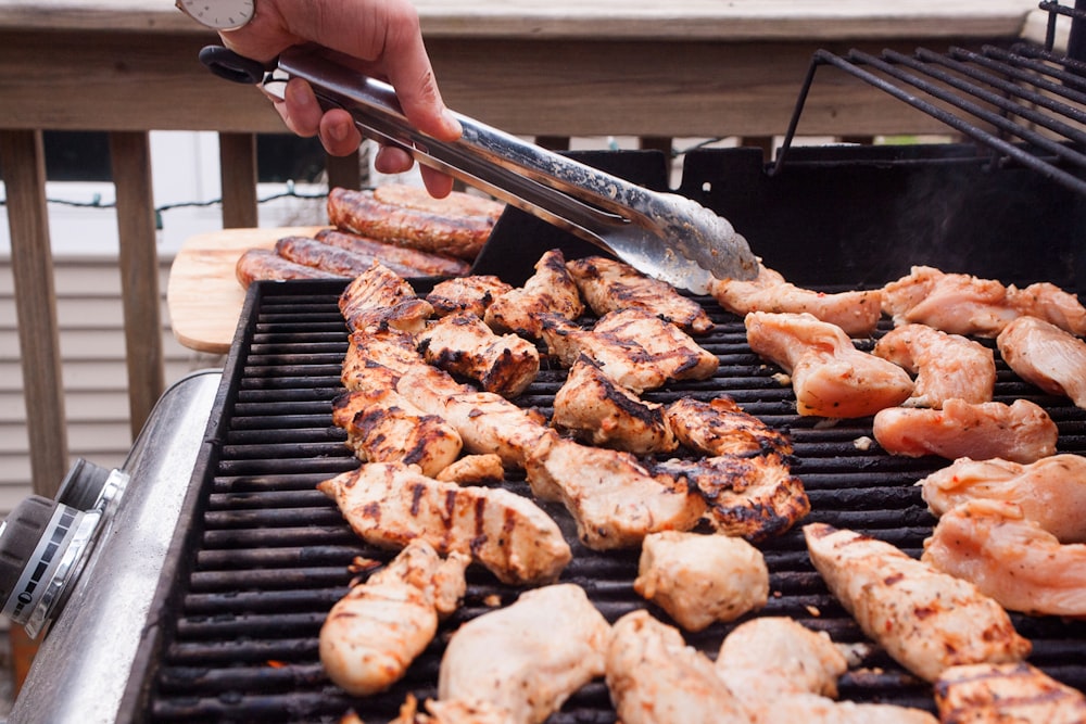 a person grilling chicken and shrimp on a grill
