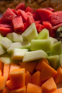 A close-up of assorted colorful fruit slices arranged neatly on a marble countertop.