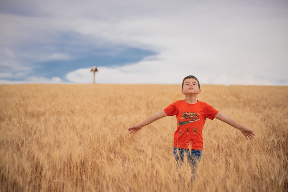 a young boy standing in a field of wheat