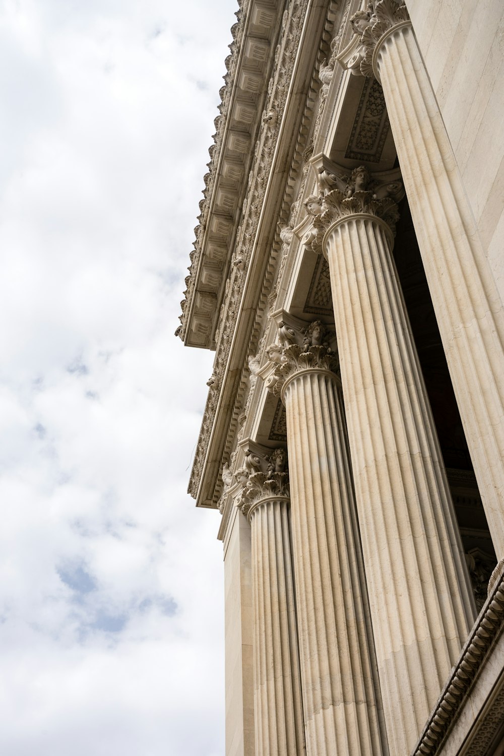 a tall building with columns and a clock on the side of it