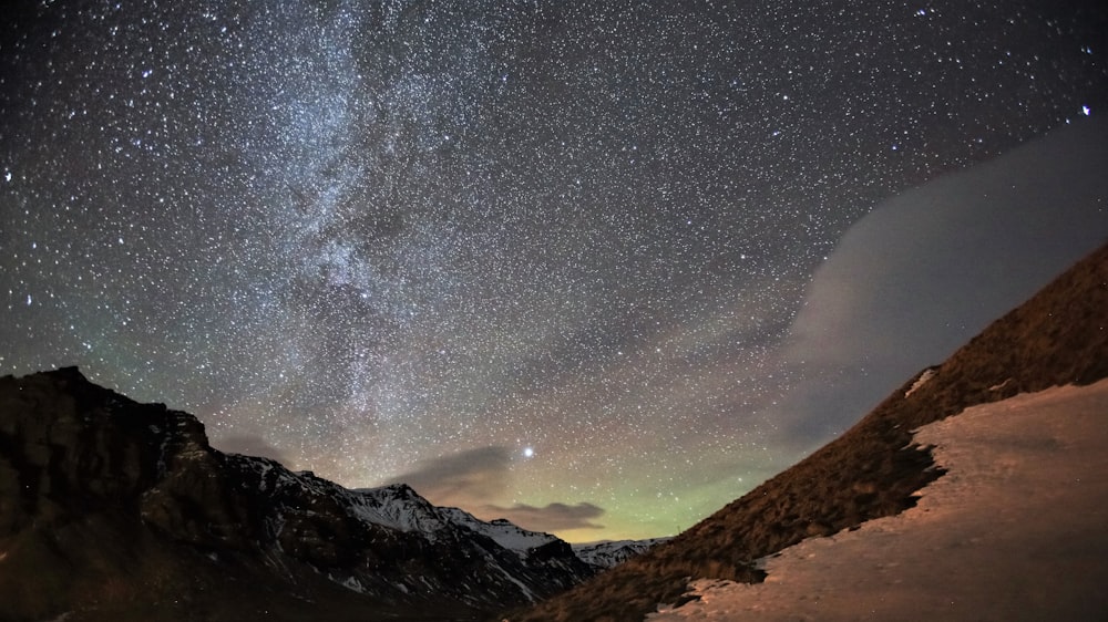 the night sky with stars above a mountain