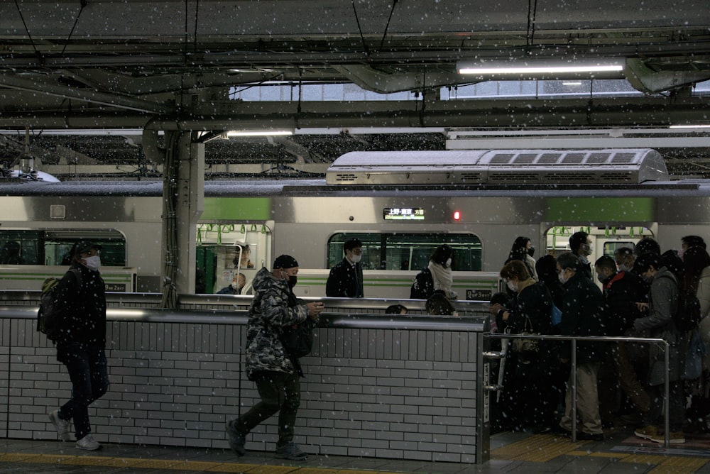 a group of people standing next to a subway train