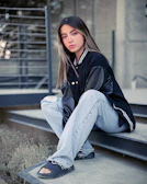 Casual streetwear outfit featuring oversized denim jacket and white sneakers on urban steps.