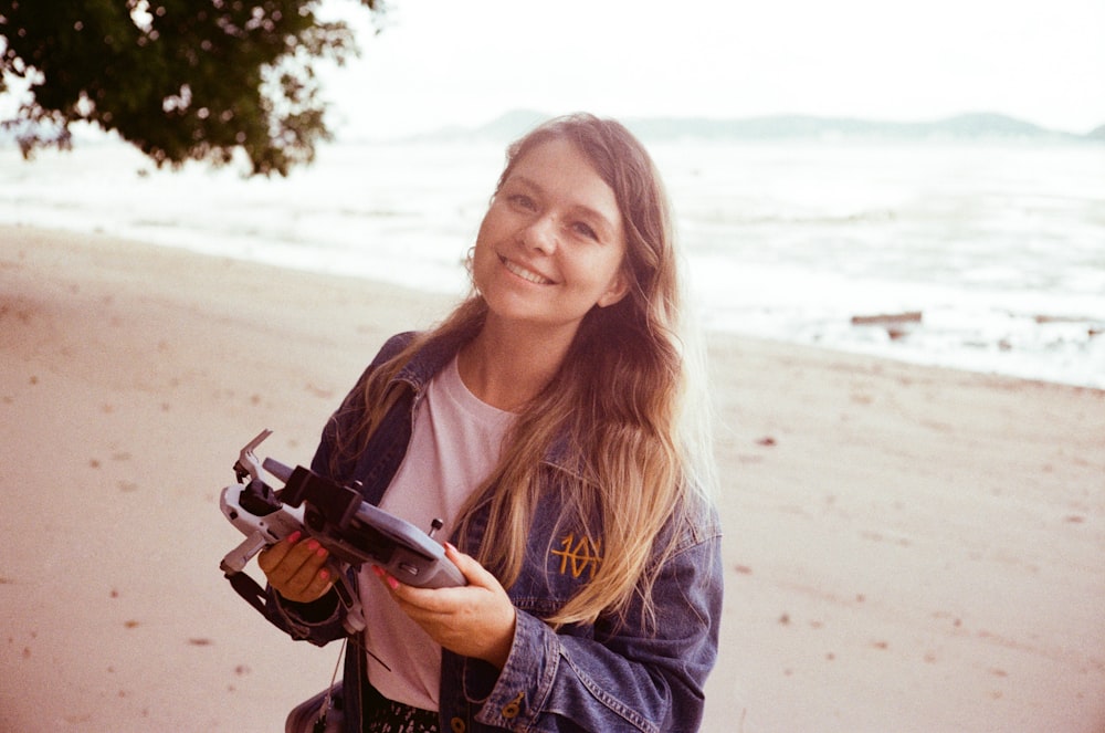 a woman standing on a beach holding a camera