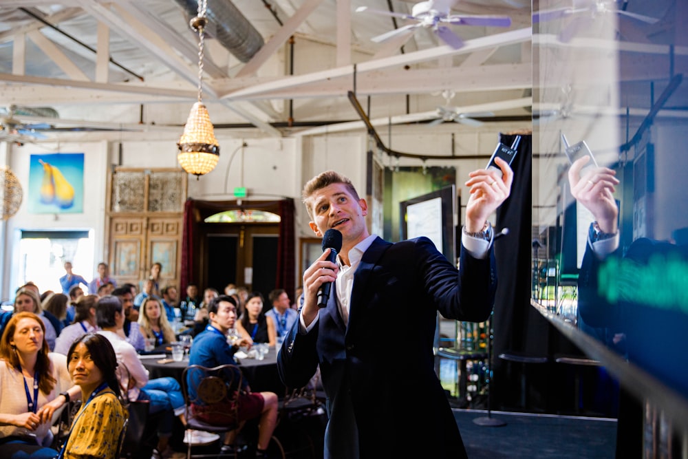 a man standing in front of a crowd holding a microphone