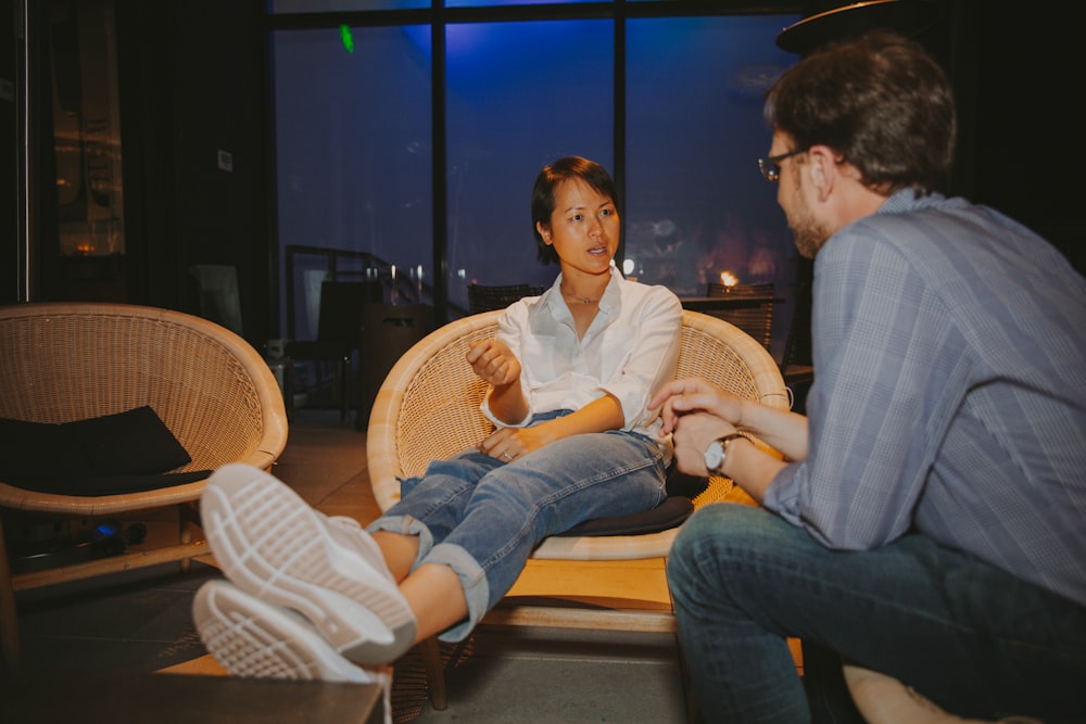 a man and a woman sitting on a wicker chair