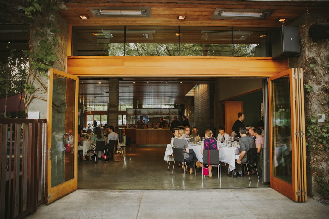 a group of people sitting at a table outside of a restaurant, Business executives dining during a garden lunch meeting a