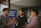 Three individuals are engaged in conversation in a bar or cafe setting. One person is gesturing with their hand while the others smile, suggesting a positive interaction. Behind them, a banner displays the words 'Connect, Grow, Thrive.'.
