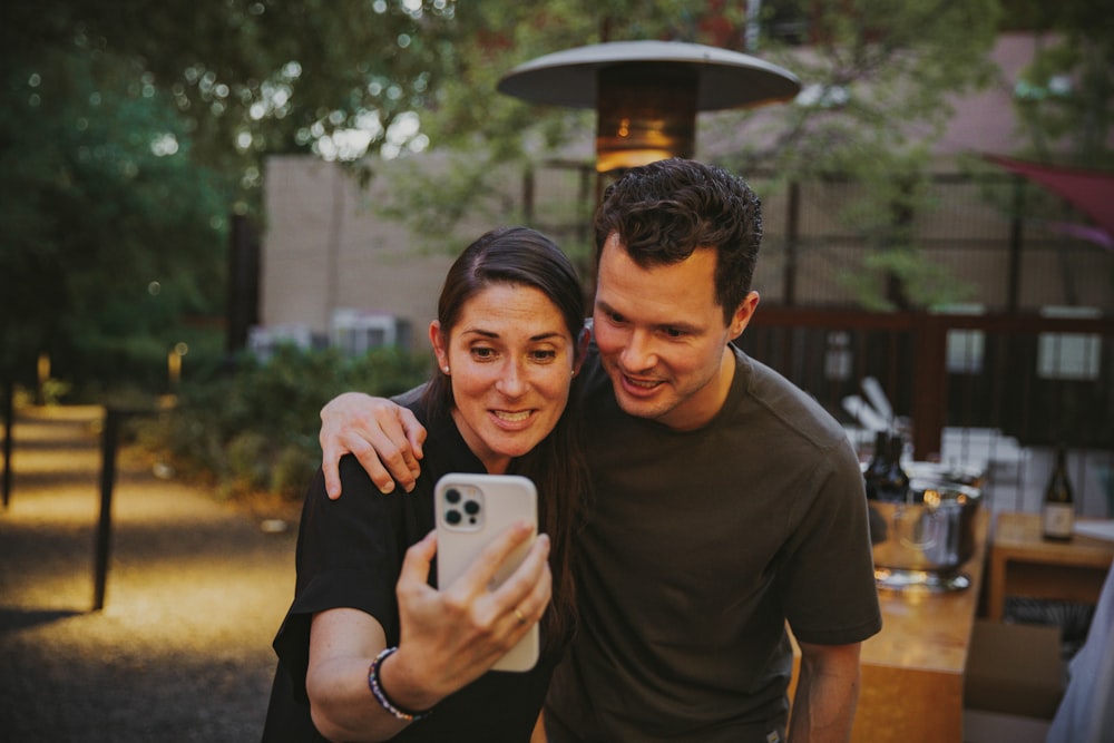 a man and woman taking a selfie with a cell phone