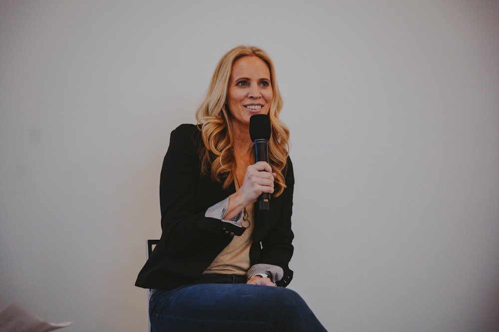 a woman sitting in a chair holding a microphone