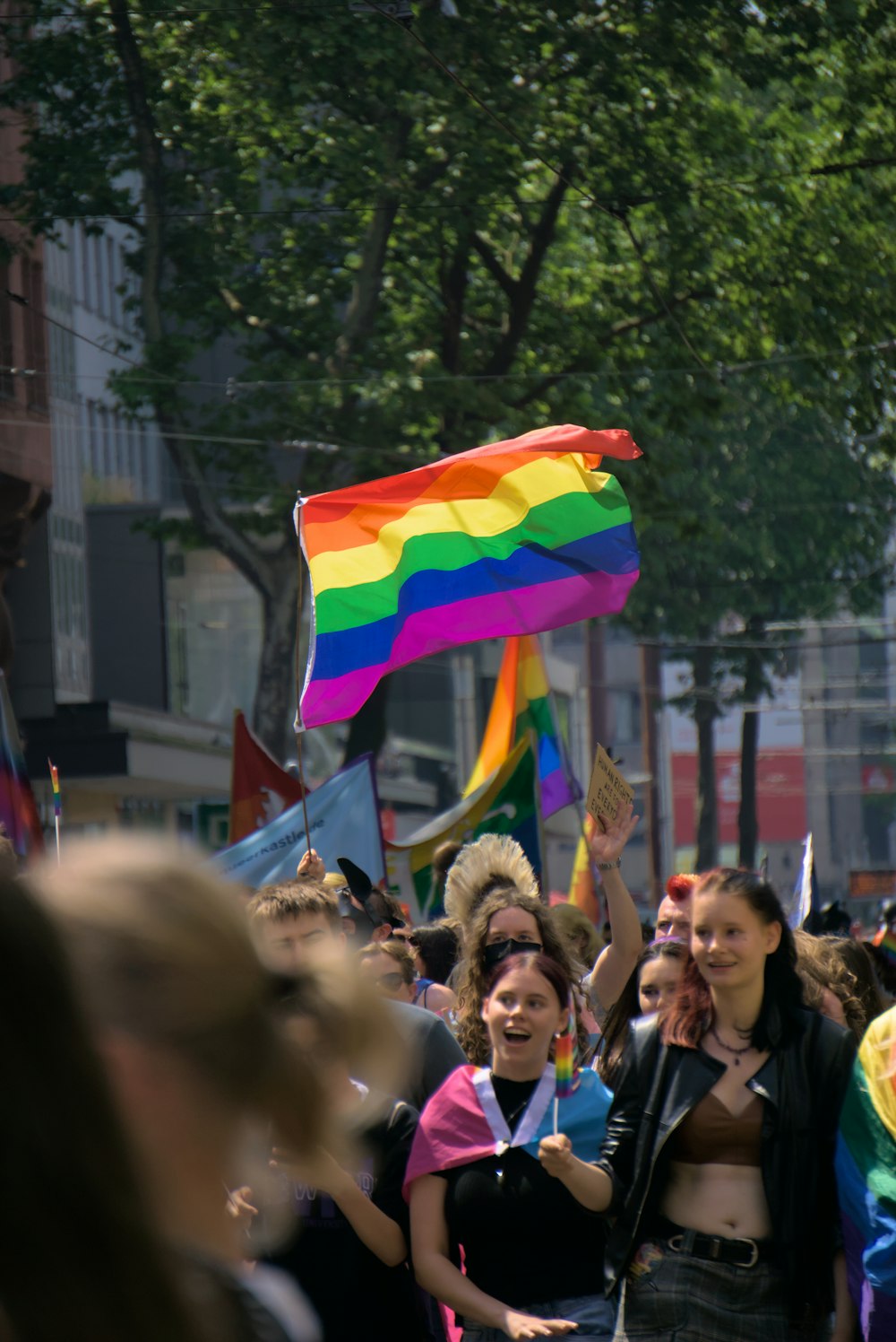 a group of people walking down a street holding a rainbow flag