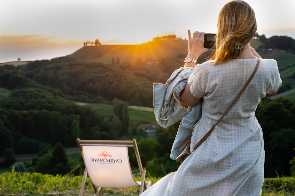 a woman taking a picture of the sunset