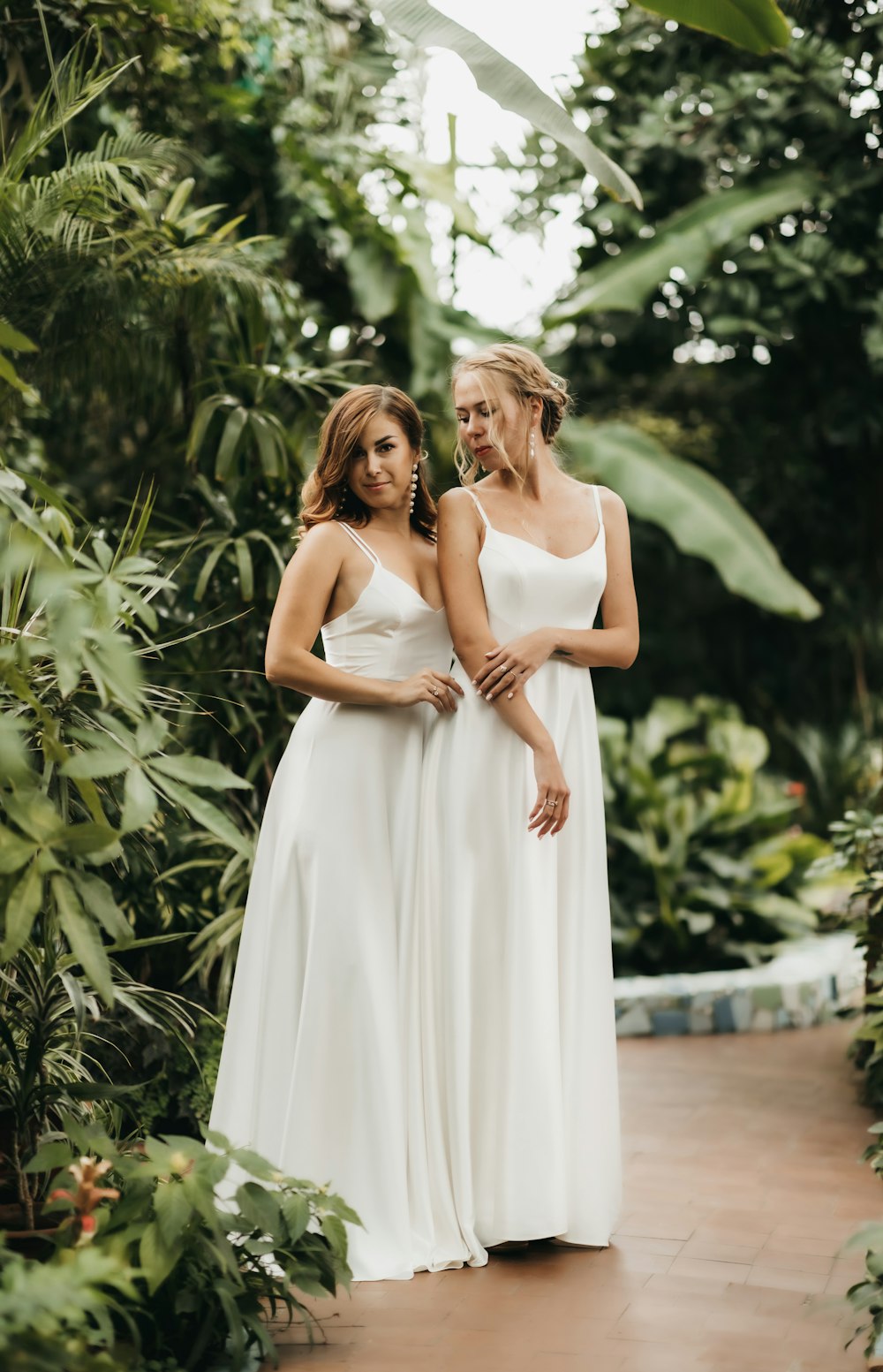 two women in white dresses standing next to each other