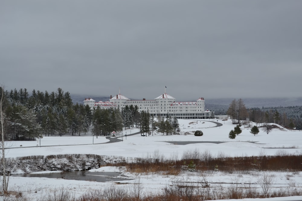Un grande edificio bianco seduto in cima a un campo coperto di neve