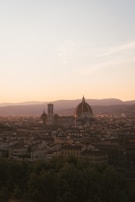 A panoramic view of a historic city skyline at dawn, bathed in soft golden light.