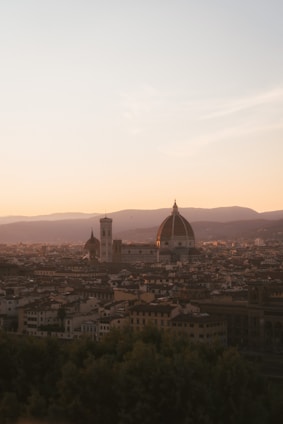 A panoramic view of the Dome of the Rock and the Church of the Holy Sepulcher under a golden sunset.
