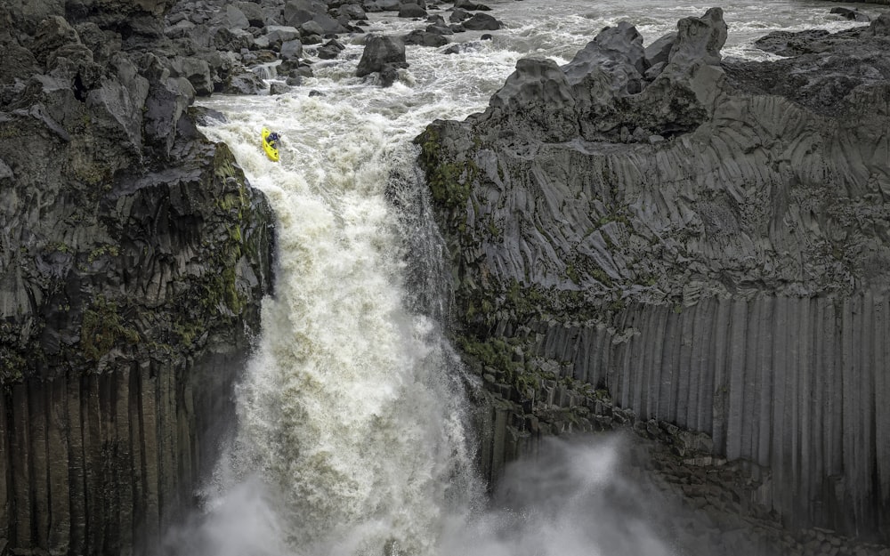 a yellow kayak is in the middle of a waterfall