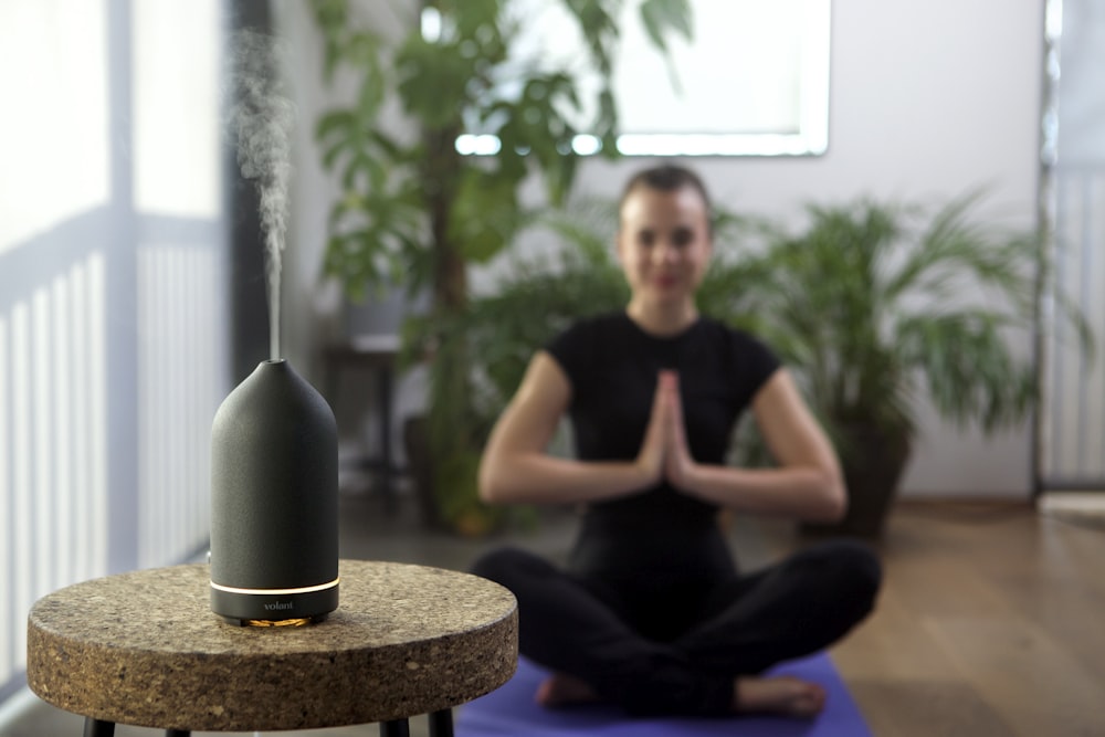 a woman sitting on a yoga mat in a room